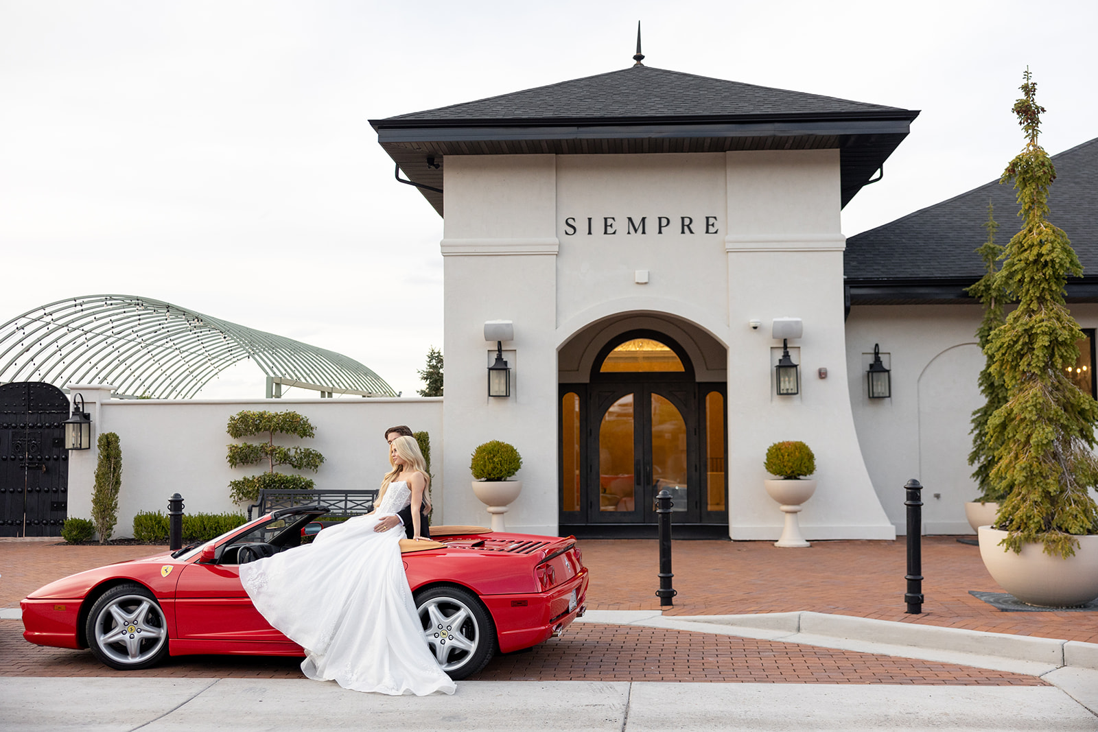 Photo of wedding couple with red ferrari in front of siempre utah wedding venue